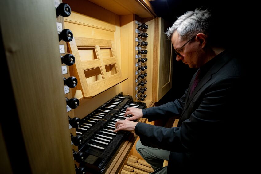 Das Foto zeigt Krysztof Urbaniak an einer Orgel, an der er spielt.