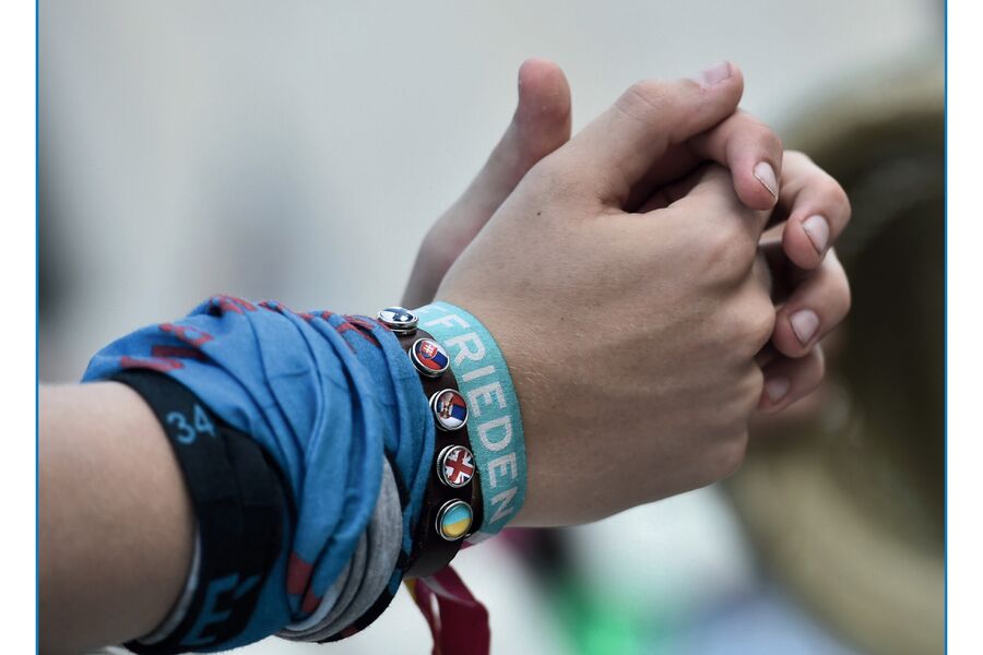 Hände eines jungen Menschen zusammengelegt; Freundschaftsbänder "Frieden"